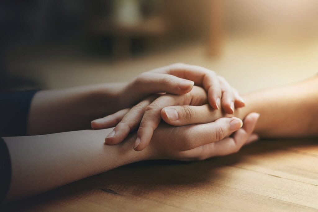 Two people holding hands across a wooden table